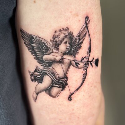 Black and grey realism cupid angel with bow and arrow tattoo by Reni Tattoo Coolangatta